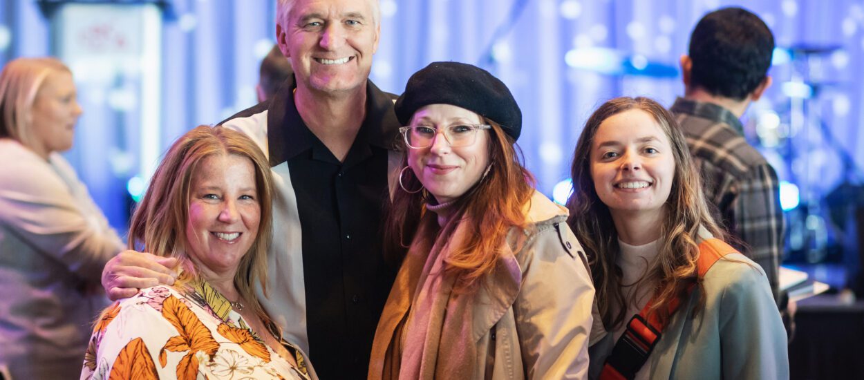 Four people pose and smile facing the camera.