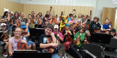 Students at East Middle School post with their musical instruments in a music classroom